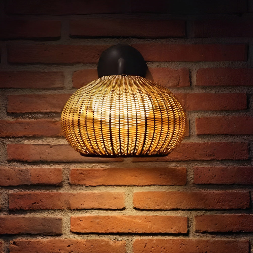 Rattan outdoor pendant light hanging above a rustic dining table in a garden setting.