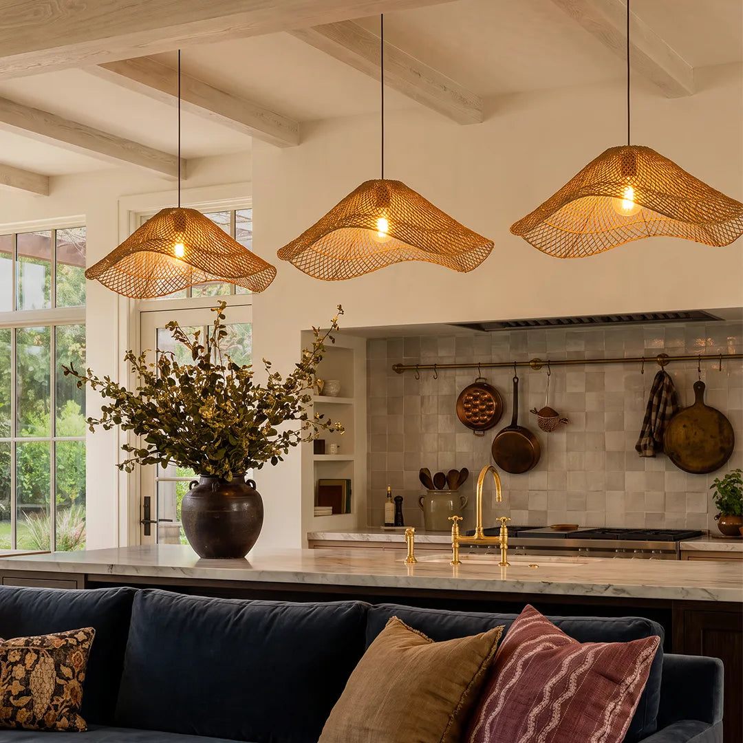 Rattan pendant light fixture trio hanging above a kitchen island in a bright rustic modern interior.