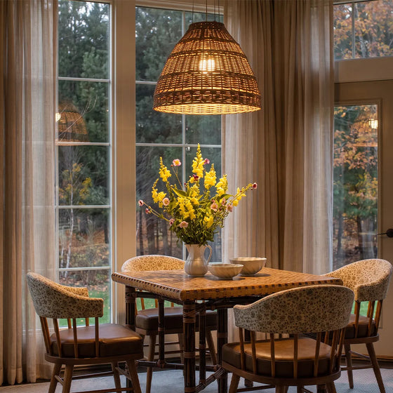Rattan pendants lights hanging above a round dining table in a cozy dining area with large windows.