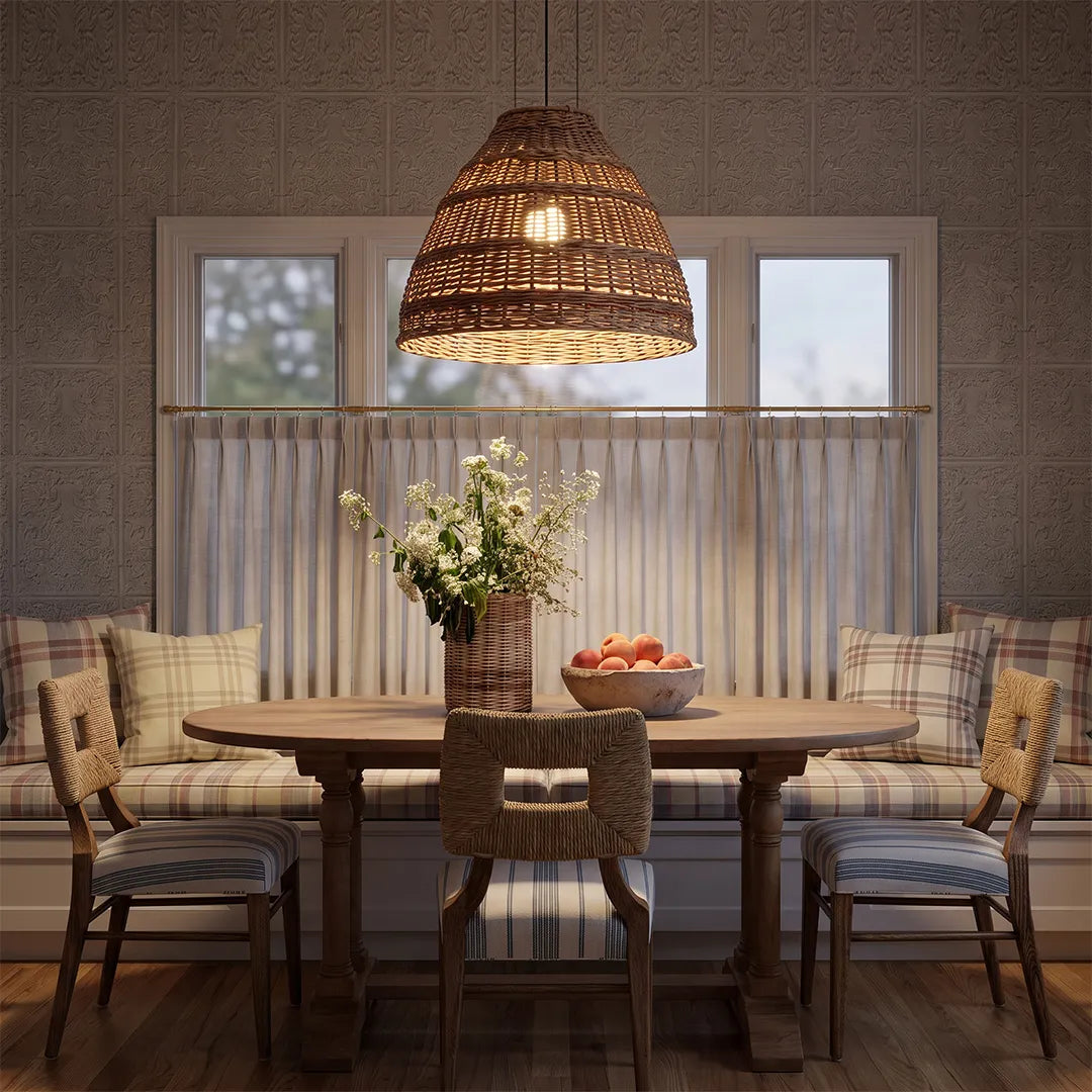 Rattan pendants lights suspended above a wooden dining table in a warm dining room with upholstered chairs.