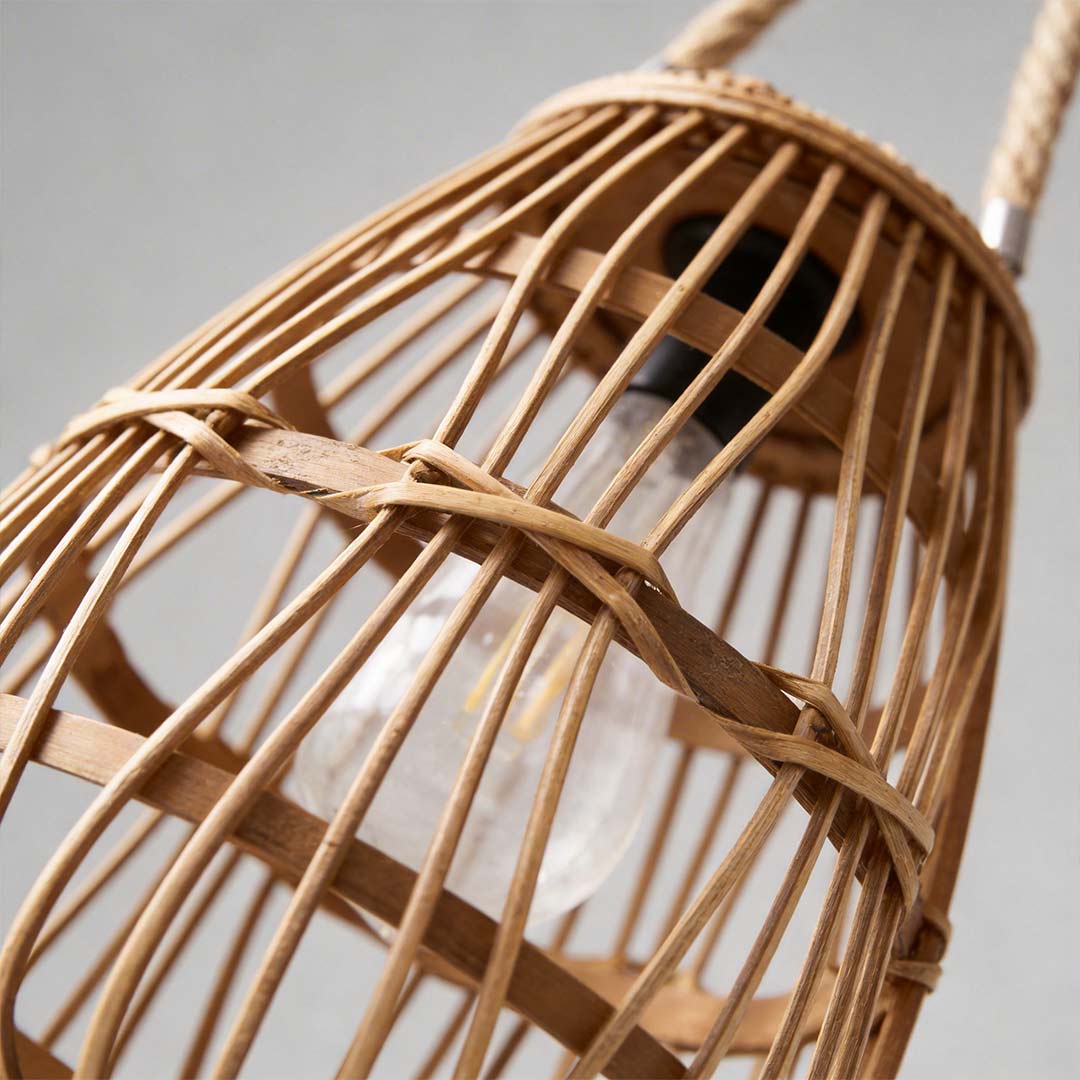 Rattan solar lantern with a woven design, providing soft illumination near plants.