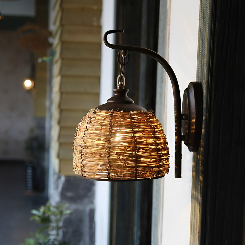 Rattan wall lamp with a black metal arm, providing soft lighting in a bedroom.