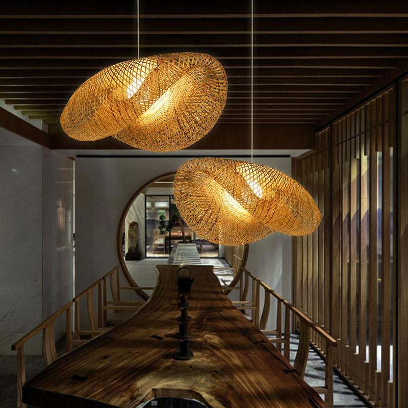 Rattan wave pendant light hanging above a long wooden dining table in a modern corridor.