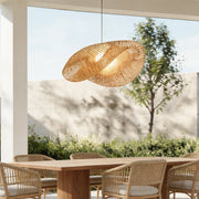 Rattan wave pendant light hanging above an outdoor dining table with natural sunlight.