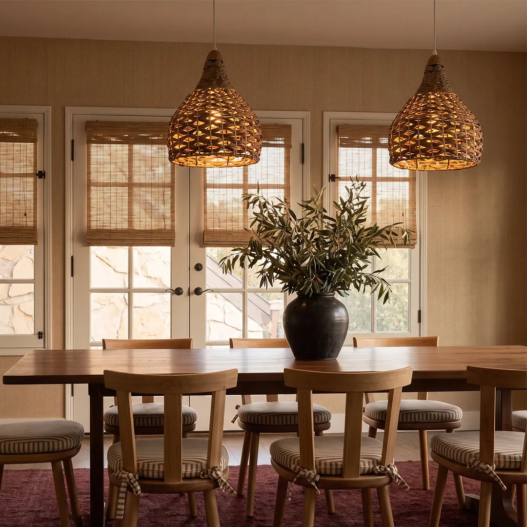 Rattan wicker pendant lights suspended above a wooden dining table in a warm dining room.