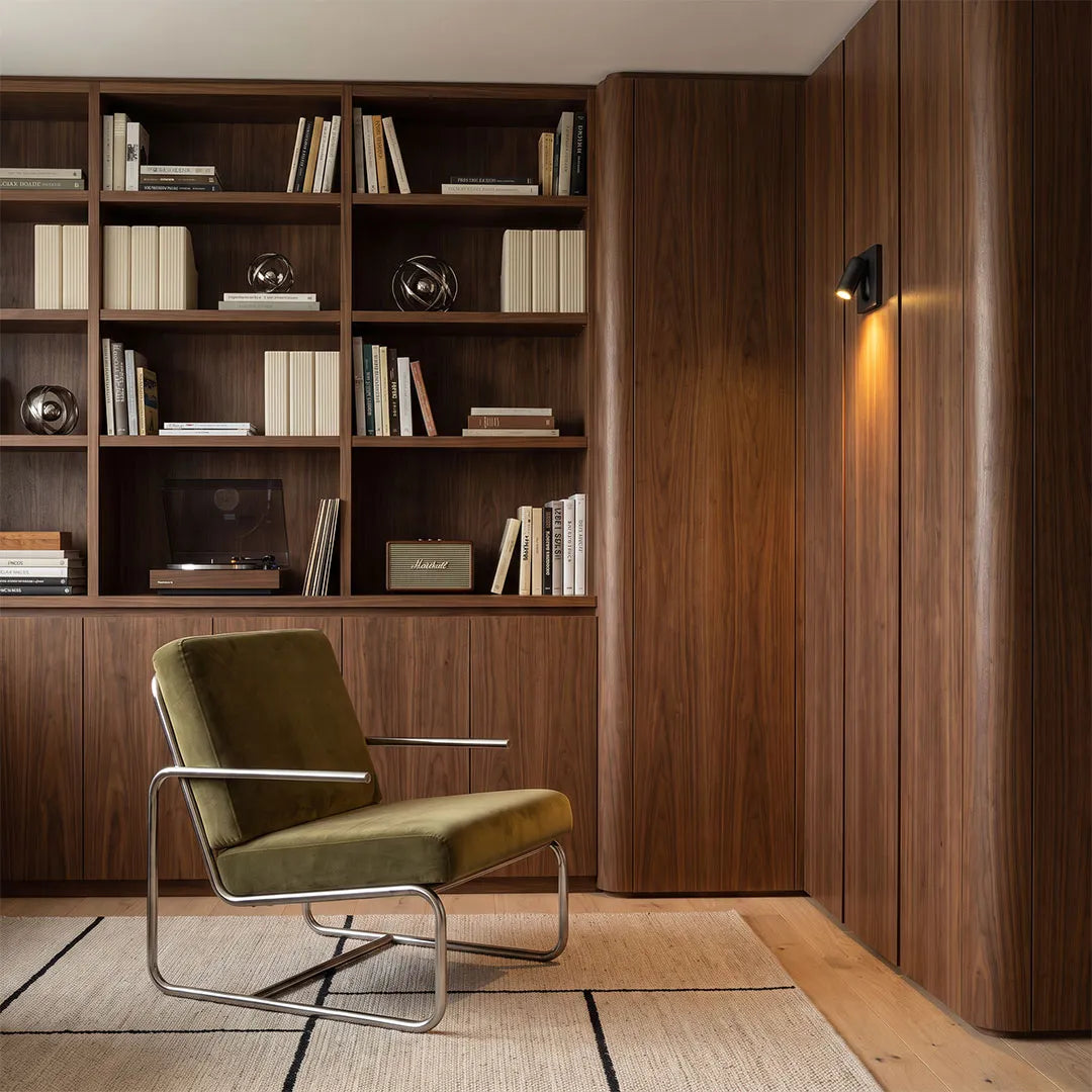 Wall mounted LED reading light providing focused illumination beside a wood-paneled reading chair.