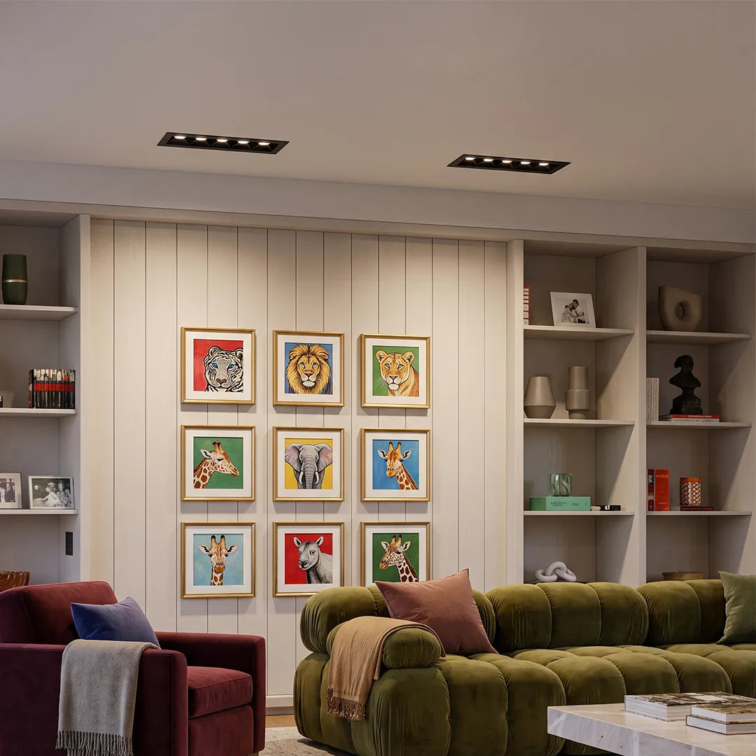 Recessed ceiling spot lights illuminating a cozy living room with colorful wall art and built-in shelving.