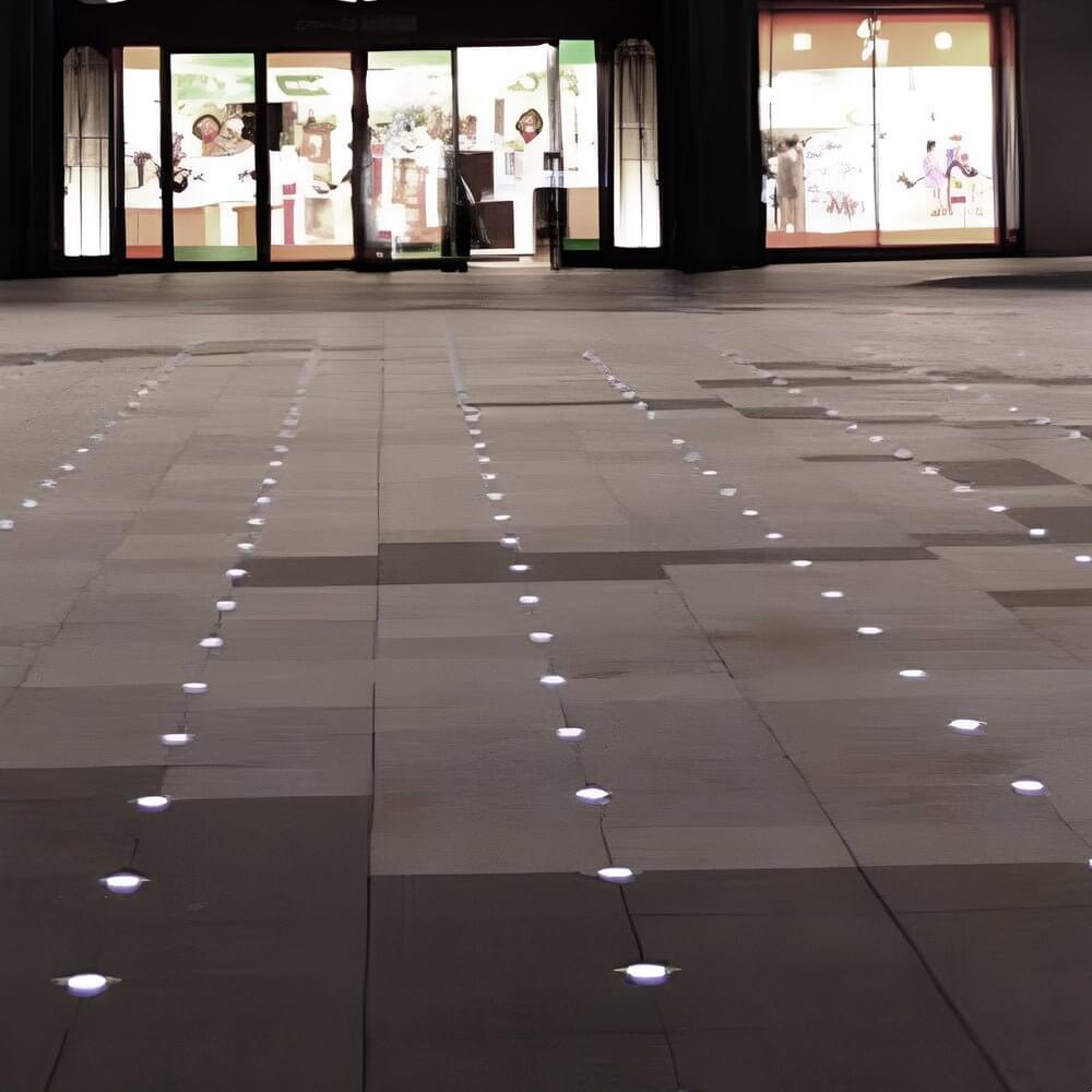 Recessed floor lighting embedded in a white tiled pathway for contemporary outdoor landscape design.