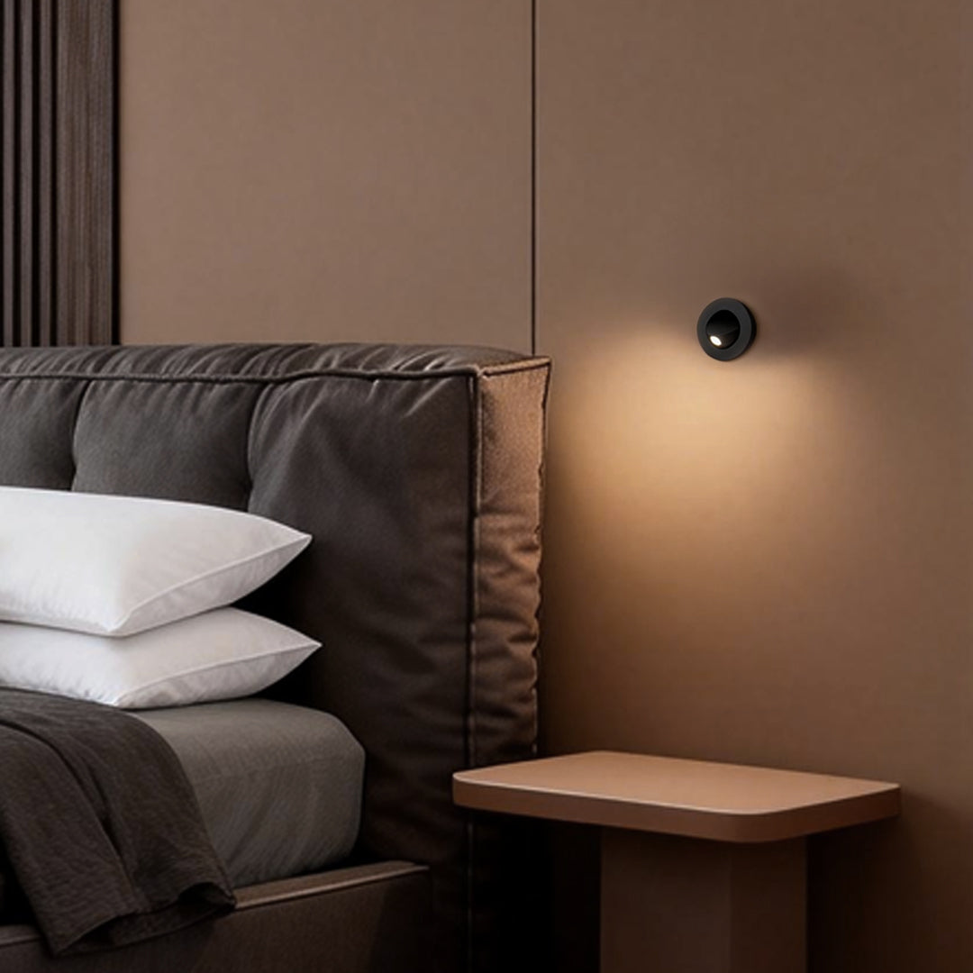 Hotel-style bedroom using recessed led reading lamp mounted beside upholstered bed.