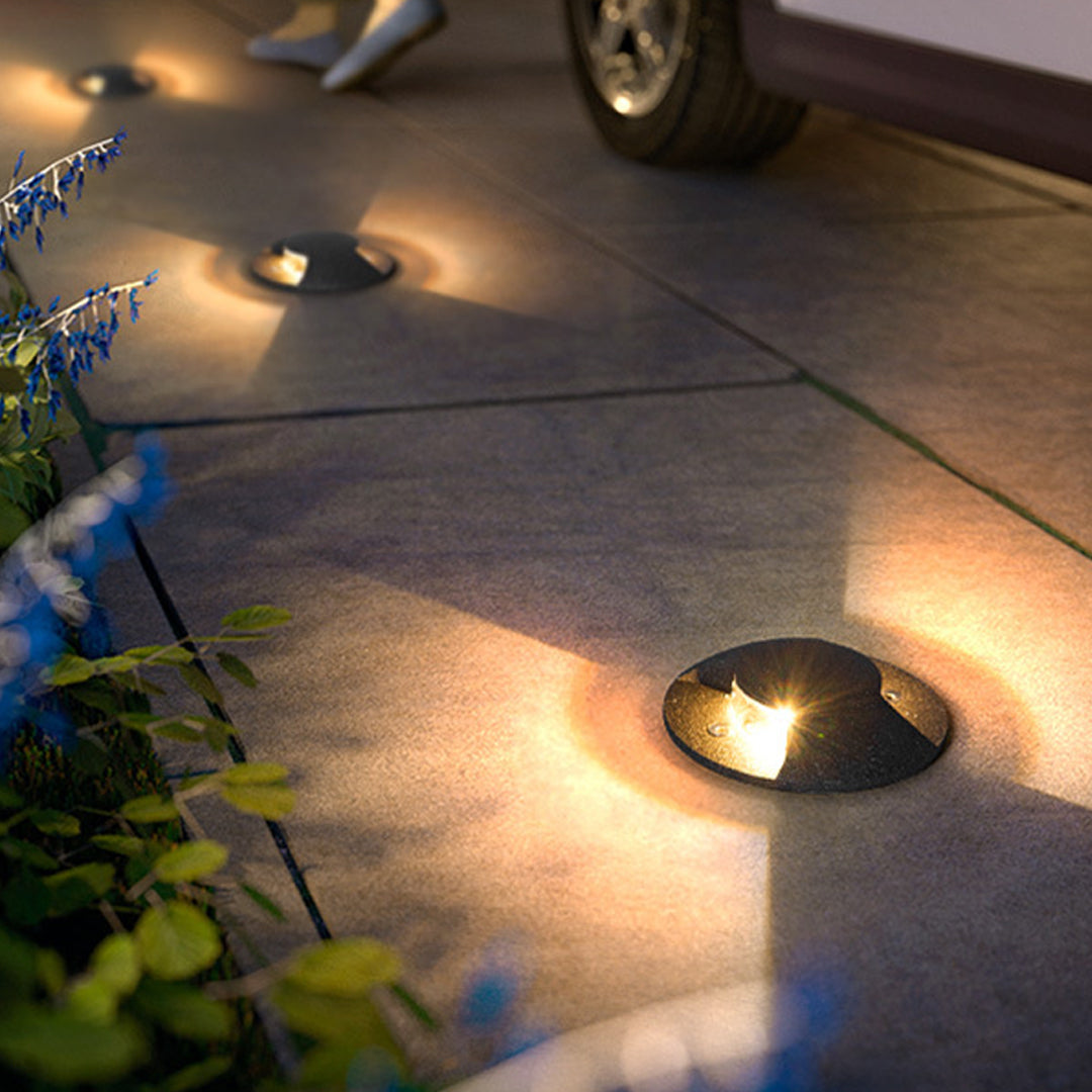 In-ground landscape lights creating dramatic uplighting effects on outdoor pathway at dusk
