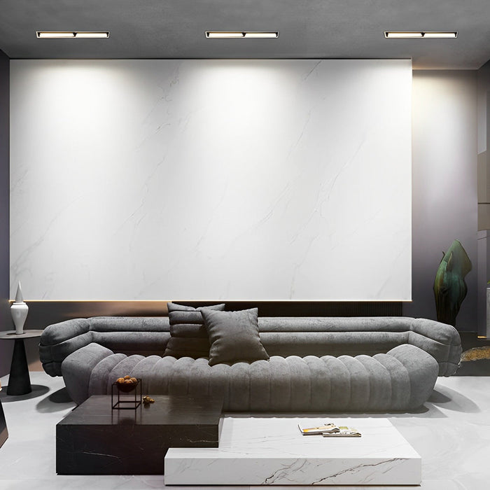 Recessed linear light fixtures installed in a modern living room ceiling