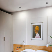 Recessed spotlight illuminating minimalist gallery wall with wood credenza and contemporary artwork