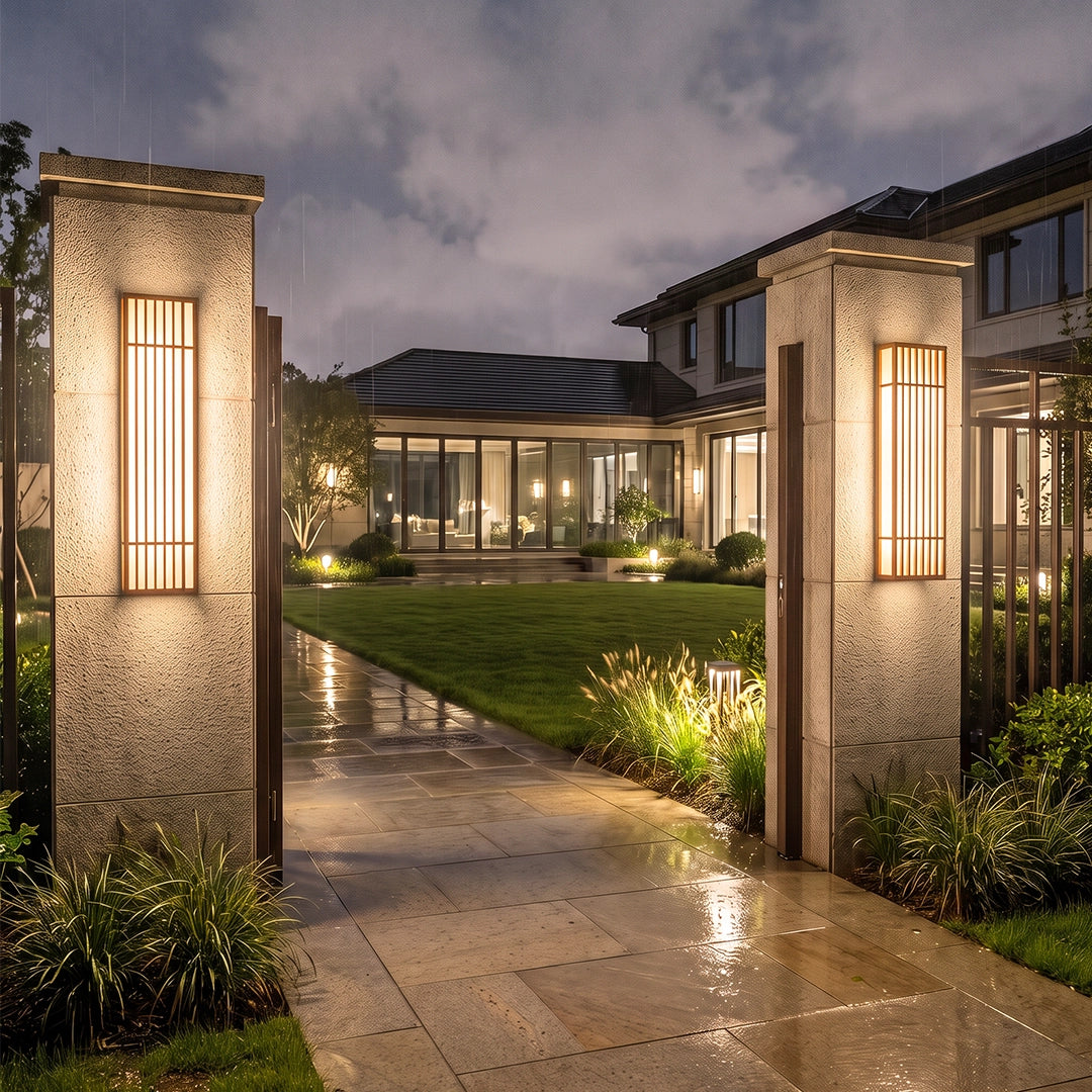 Rectangle LED outdoor wall light mounted on a stone entry wall beside a garden path at dusk.
