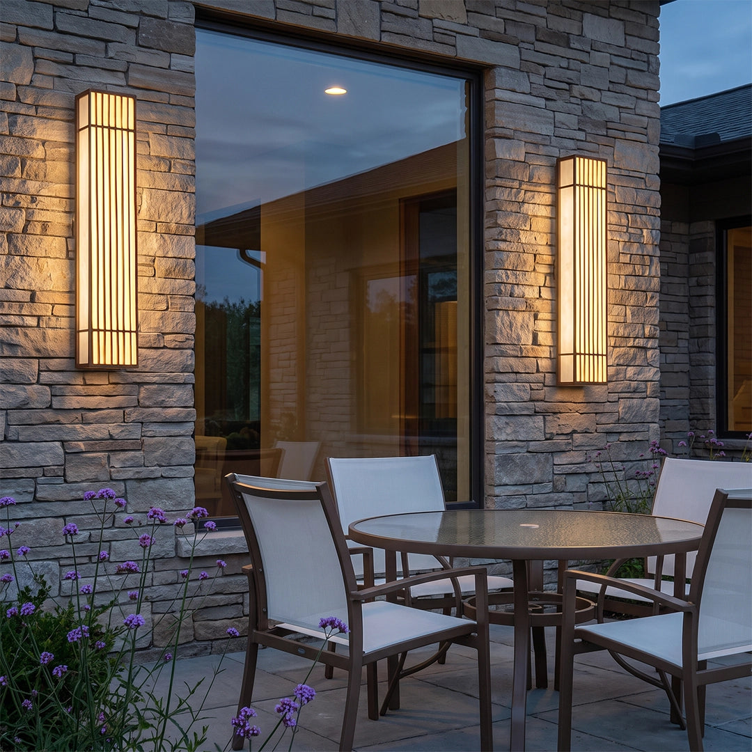 Rectangle LED outdoor wall light installed on a stone patio wall beside outdoor seating.