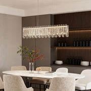 Rectangular crystal chandelier modern hanging above long dining table.