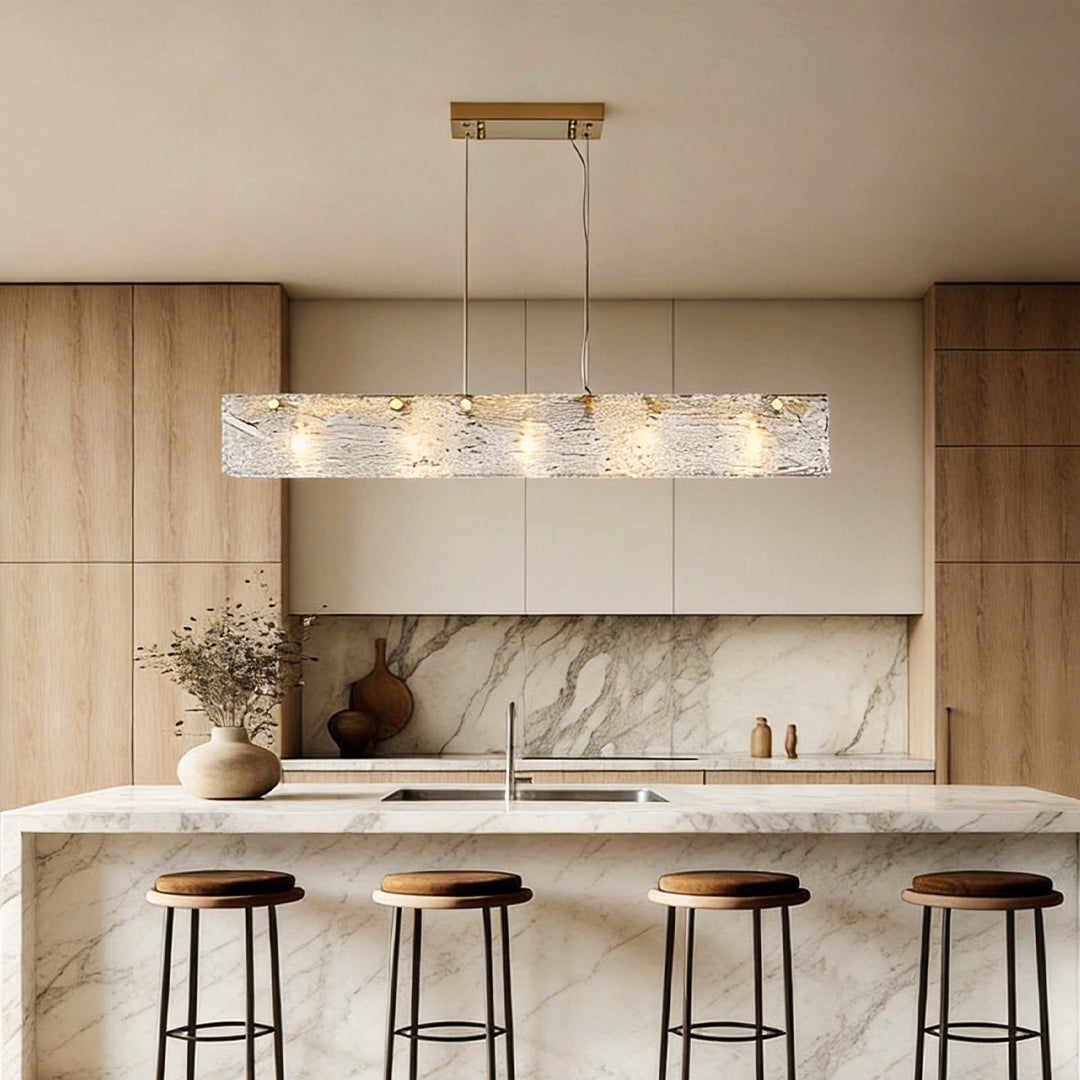 Rectangular glass chandelier with a sleek gold frame, providing elegant illumination above a modern kitchen island.