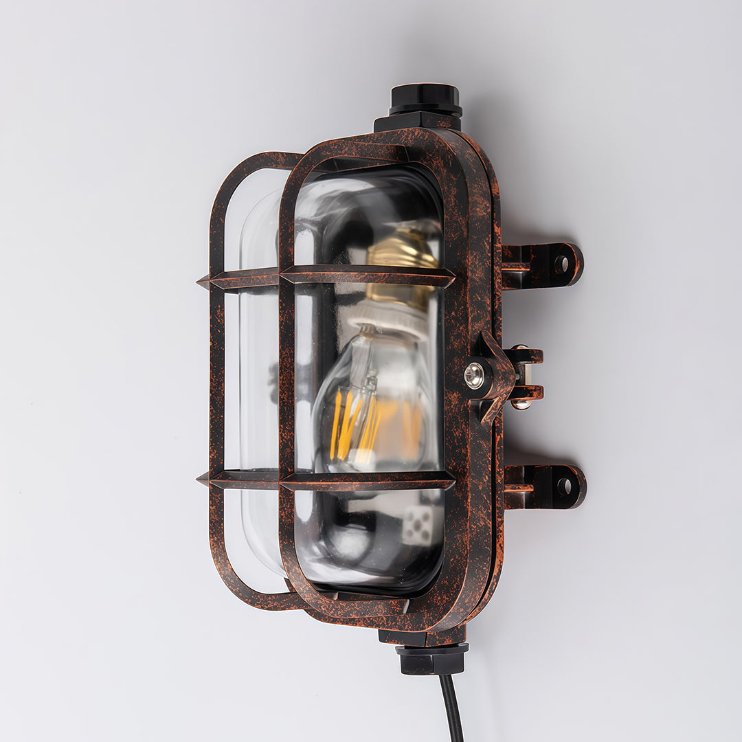 Rectangular industrial outdoor sconce with protective cage and vintage bronze finish against neutral background