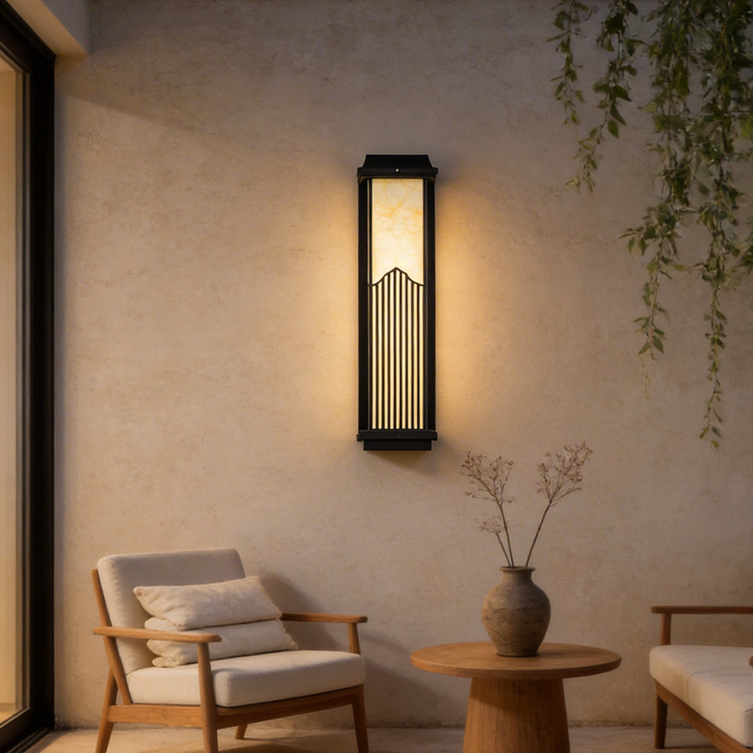 Rectangular outdoor sconce with a black frame, providing warm light near a seating area.