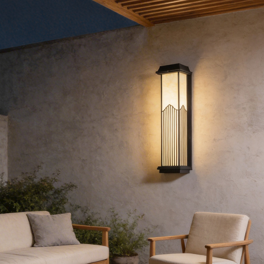 Rectangular outdoor sconce with a modern design, illuminating an exterior wall at dusk.