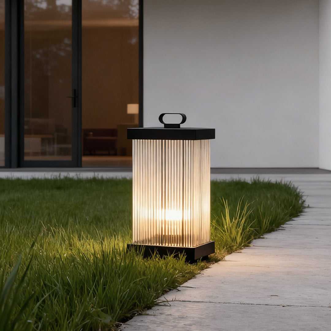 Rectangular solar lantern placed beside a garden pathway with soft warm glow.