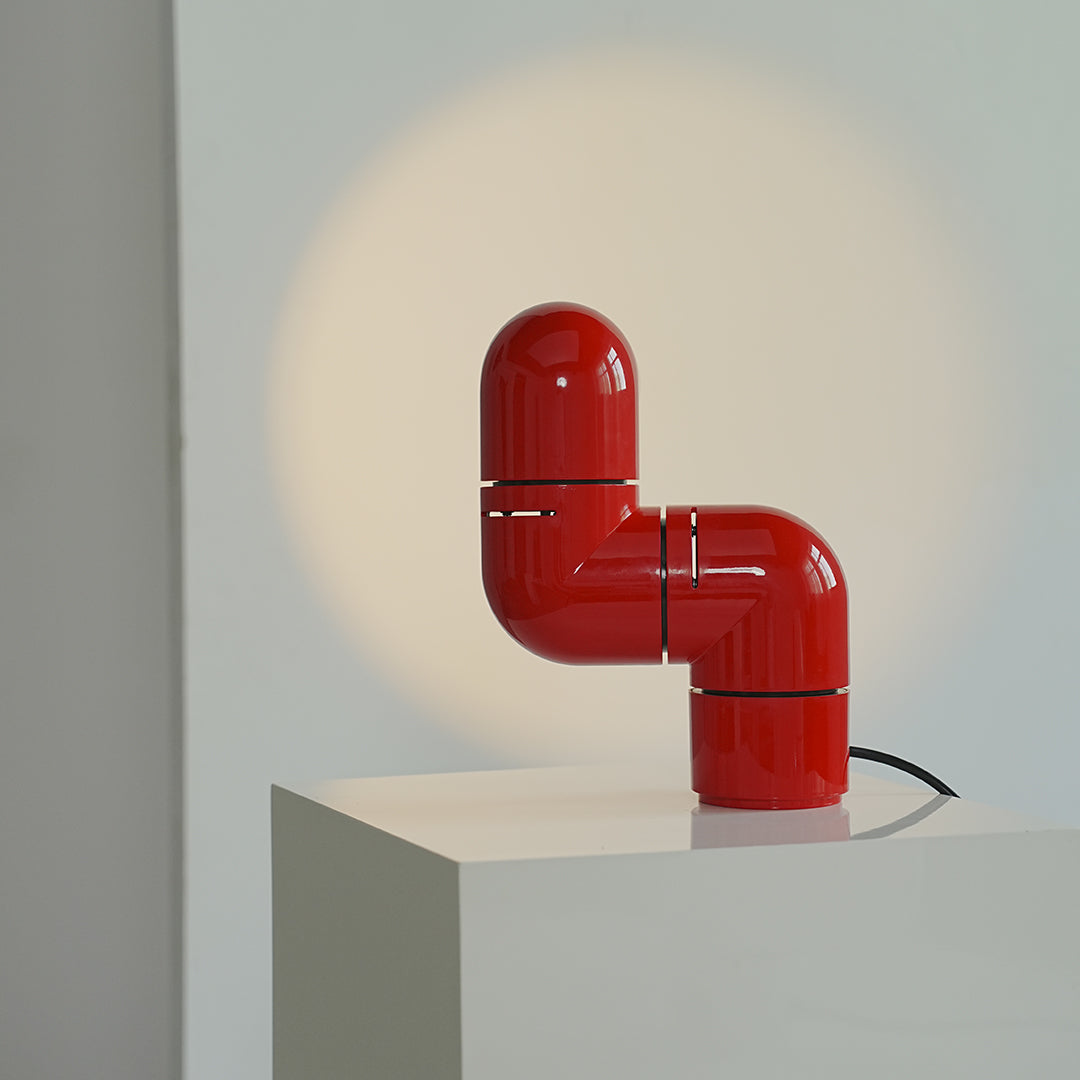 Glossy red statement table lamps highlighting minimalist geometry and bold color.