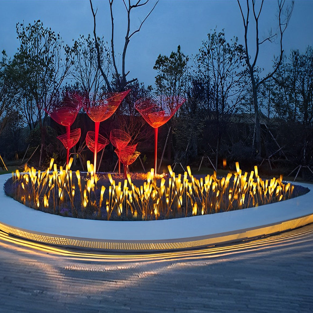 Reed lights illuminating circular garden area with modern building background.