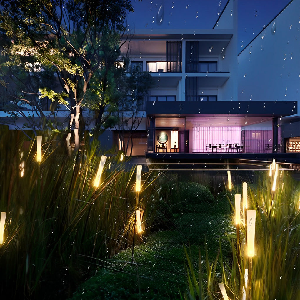 Reed lights creating magical glow in garden with trees at night.