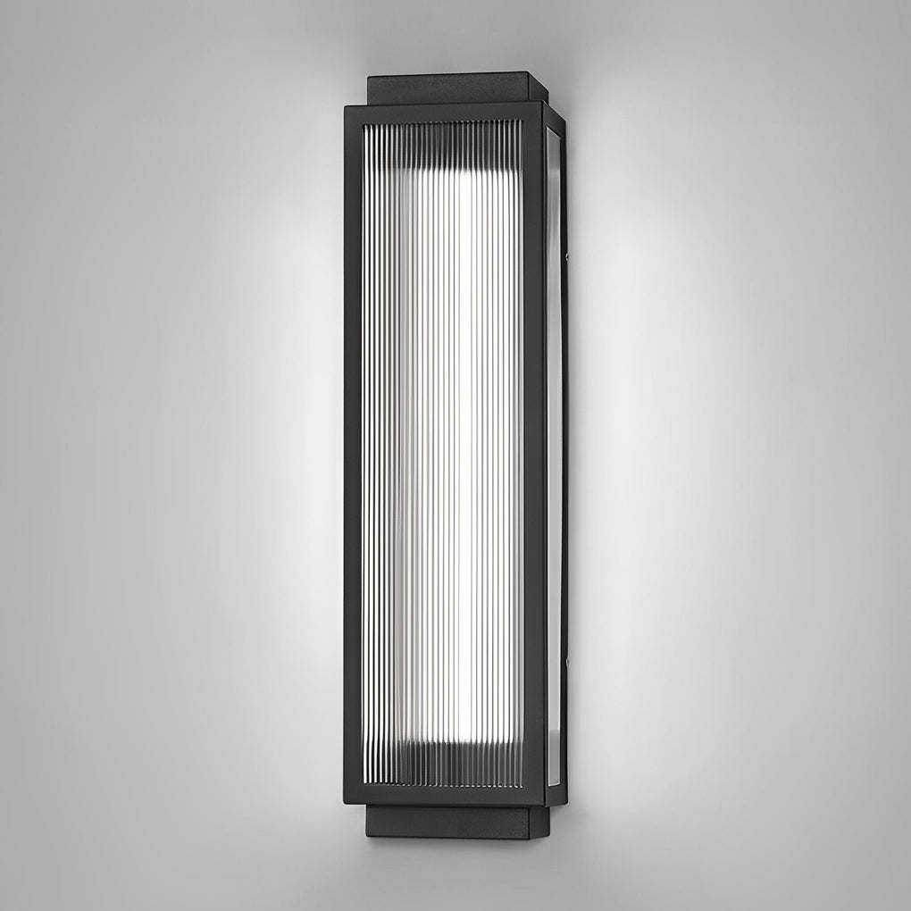 Reeded glass light fixture with a black frame, mounted vertically on a white wall for a modern look.