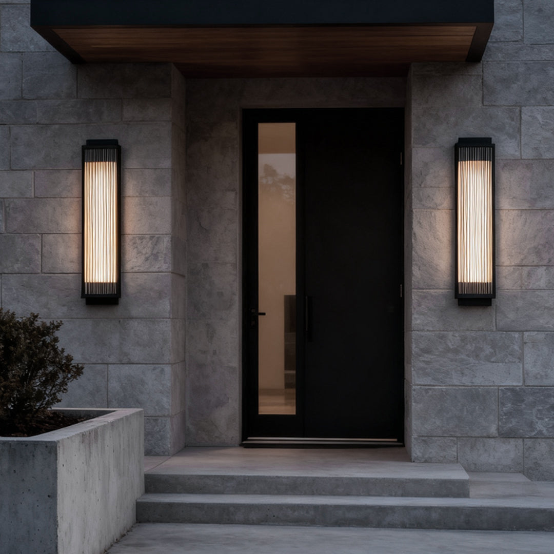 Modern outdoor wall sconce featuring reeded glass light design, mounted beside a sleek black door.