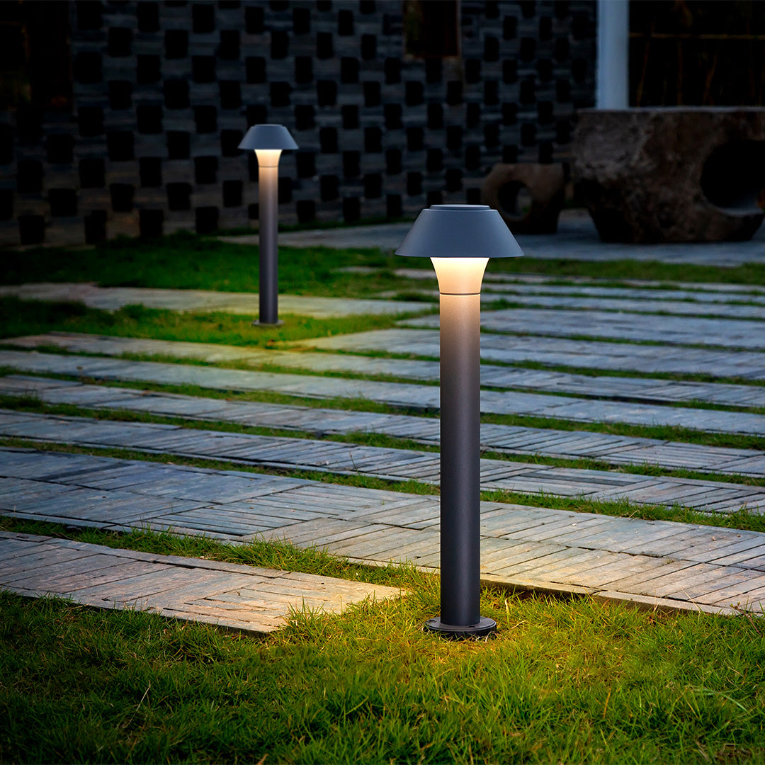 Residential bollard lights illuminating a modern garden pathway at night, providing soft guidance lighting for outdoor walkways.