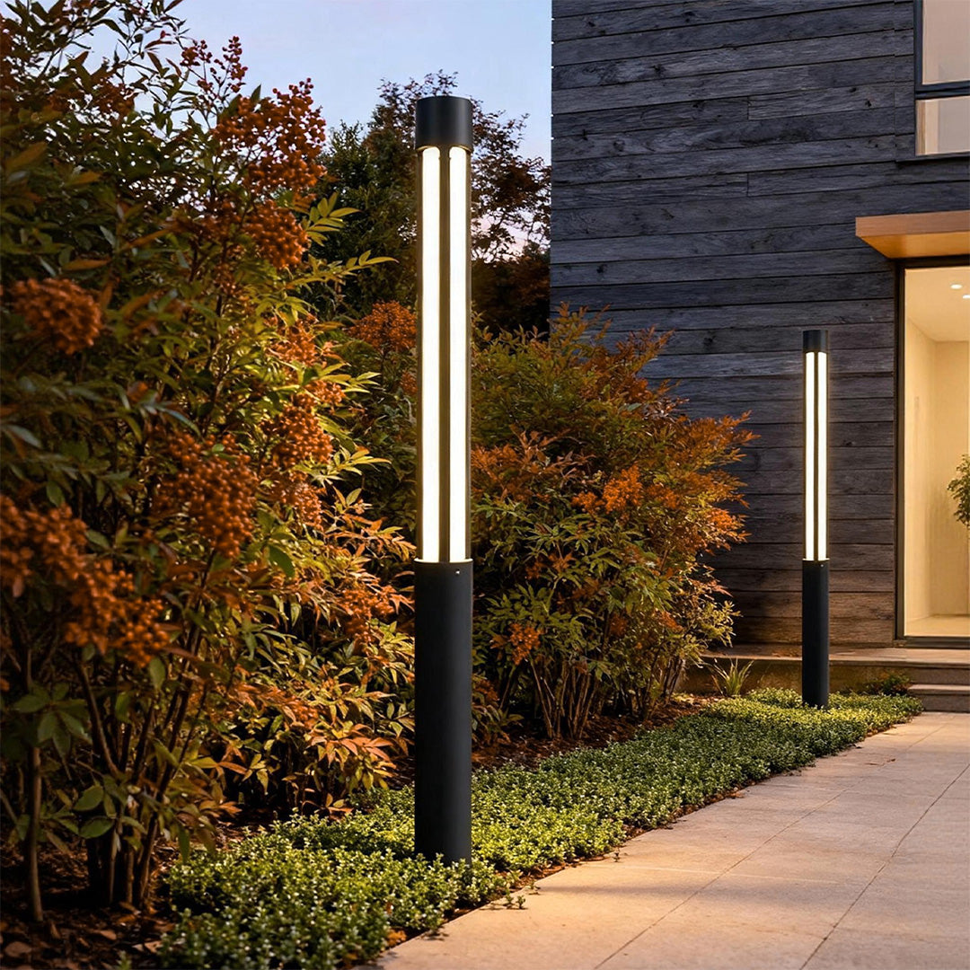 residential black cylindrical bollard lights installed along a garden walkway