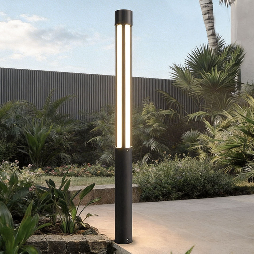 Residential bollard lights installed along a modern outdoor walkway with tropical landscaping.