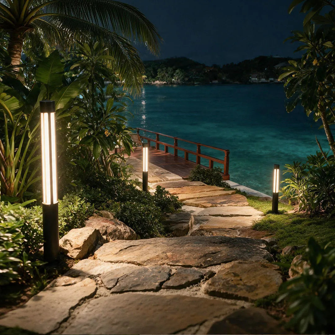 Residential bollard lights illuminating a stone path leading toward a waterfront garden at night.