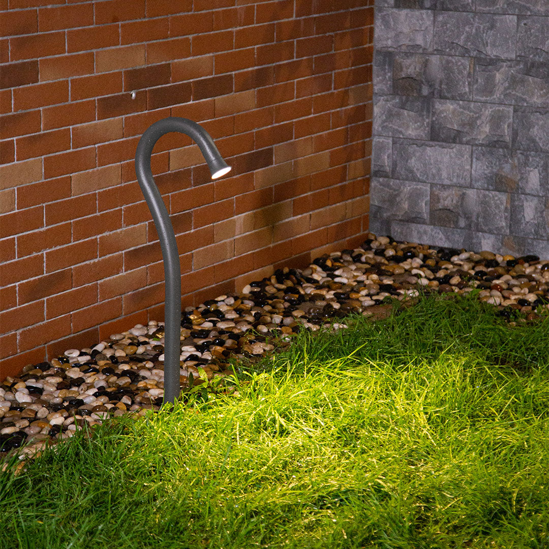 Residential landscaping featuring curved bollard lights illuminating brick wall and garden area