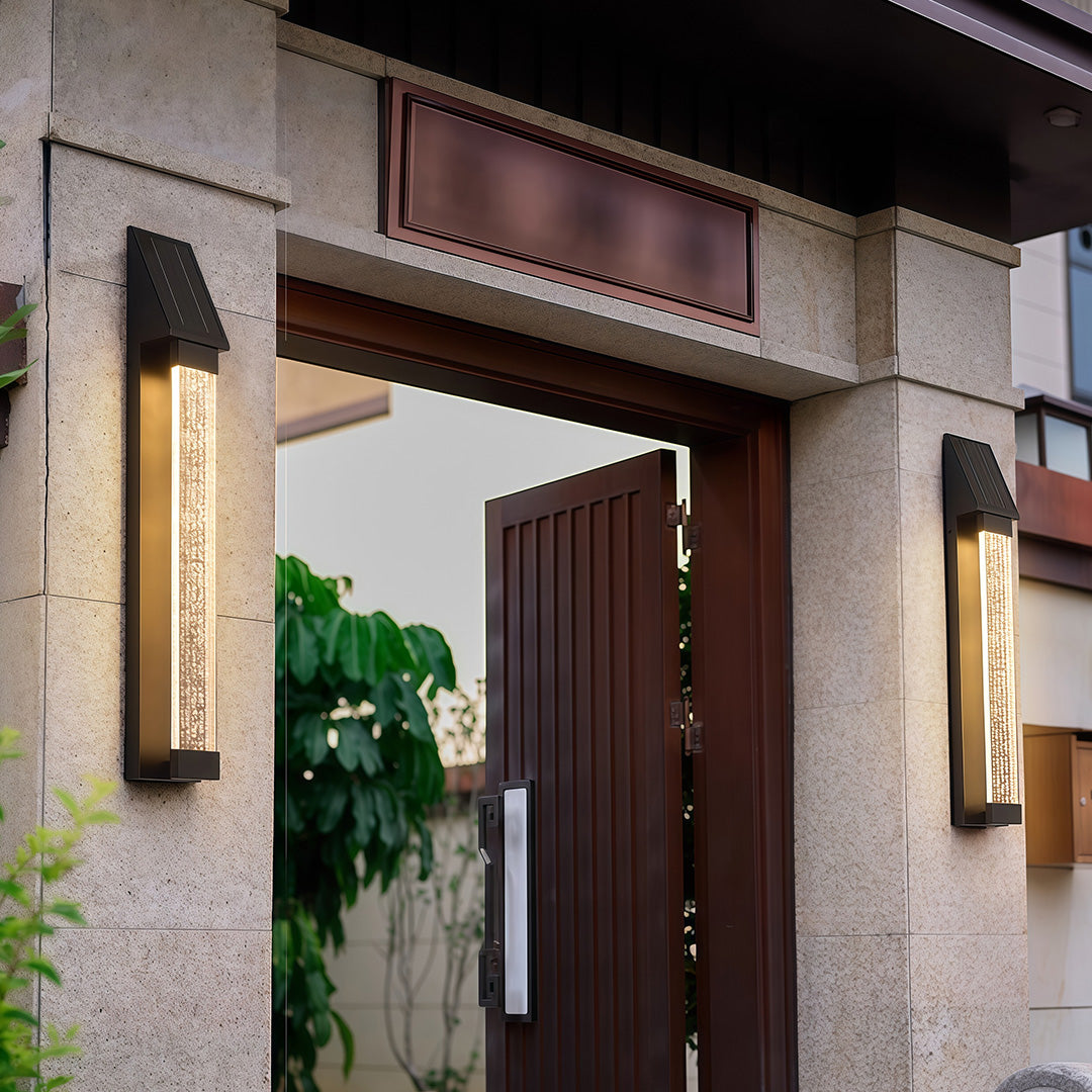 Black outdoor lighting sconce illuminating a residential entrance, creating a welcoming ambiance.