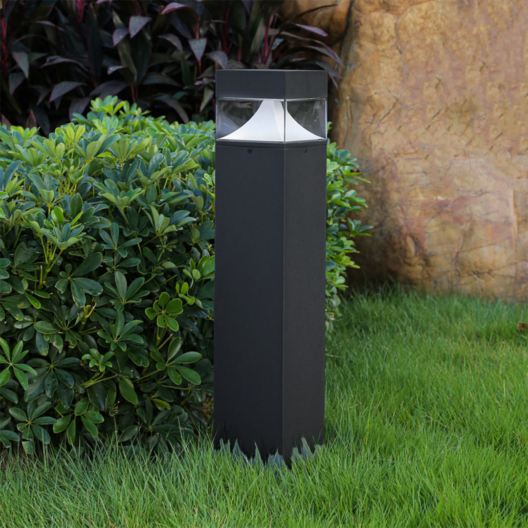 Contemporary square bollard creating warm accent lighting in residential garden landscape