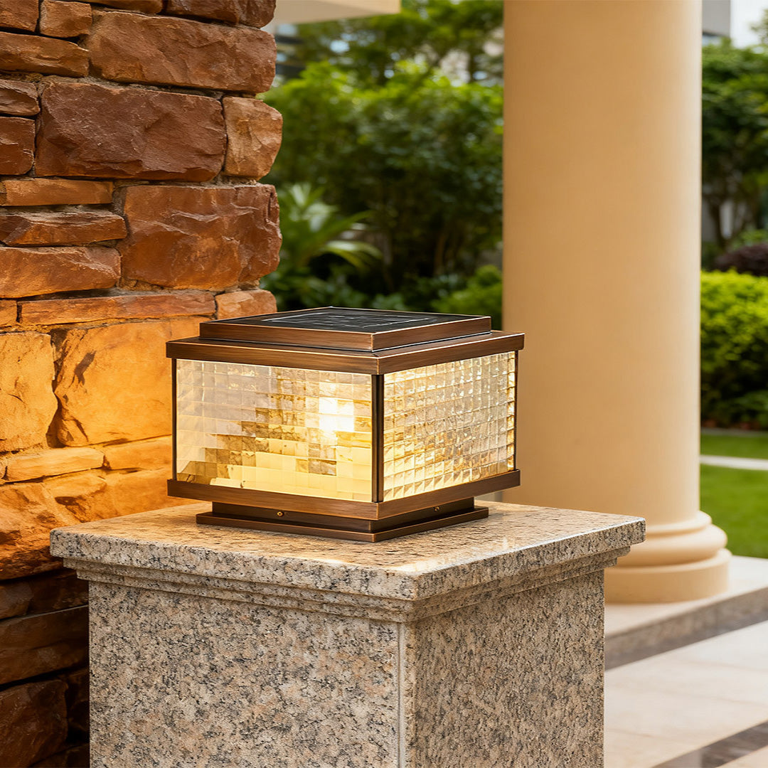 Pillar cap lights on brick stone posts framing residential driveway entrance with natural foliage backdrop