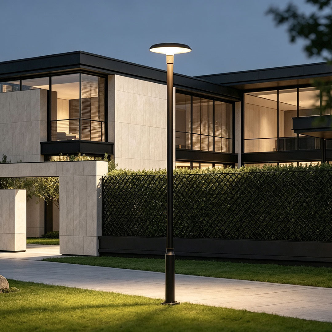 Residential street lighting beside a modern house with a tall pole light brightening the driveway and walkway.
