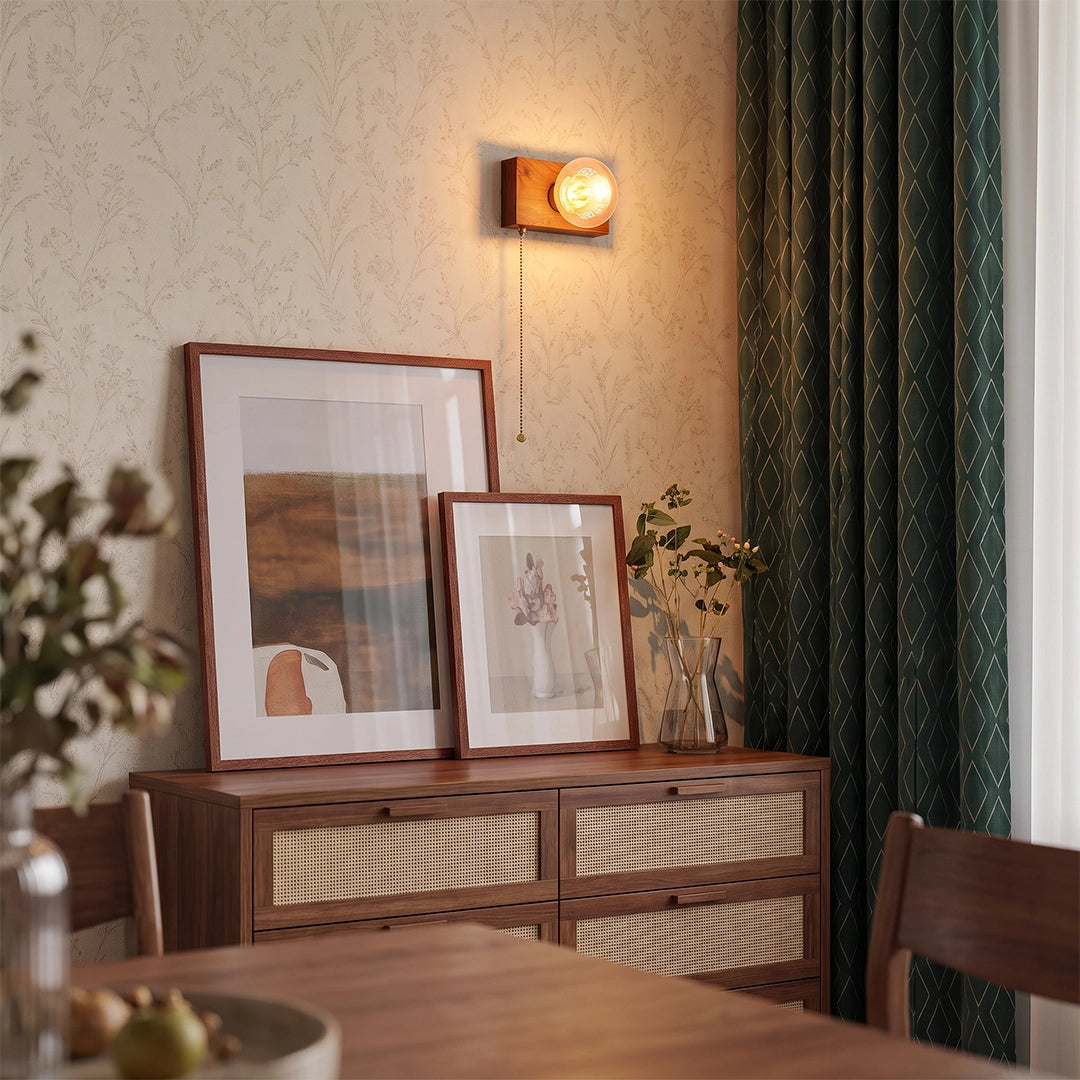 Retro bedside wall light above a wooden sideboard with framed art, adding warm ambient light.