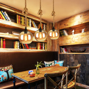 Multiple retro glass pendant lights creating atmospheric lighting in trendy cafe environment.