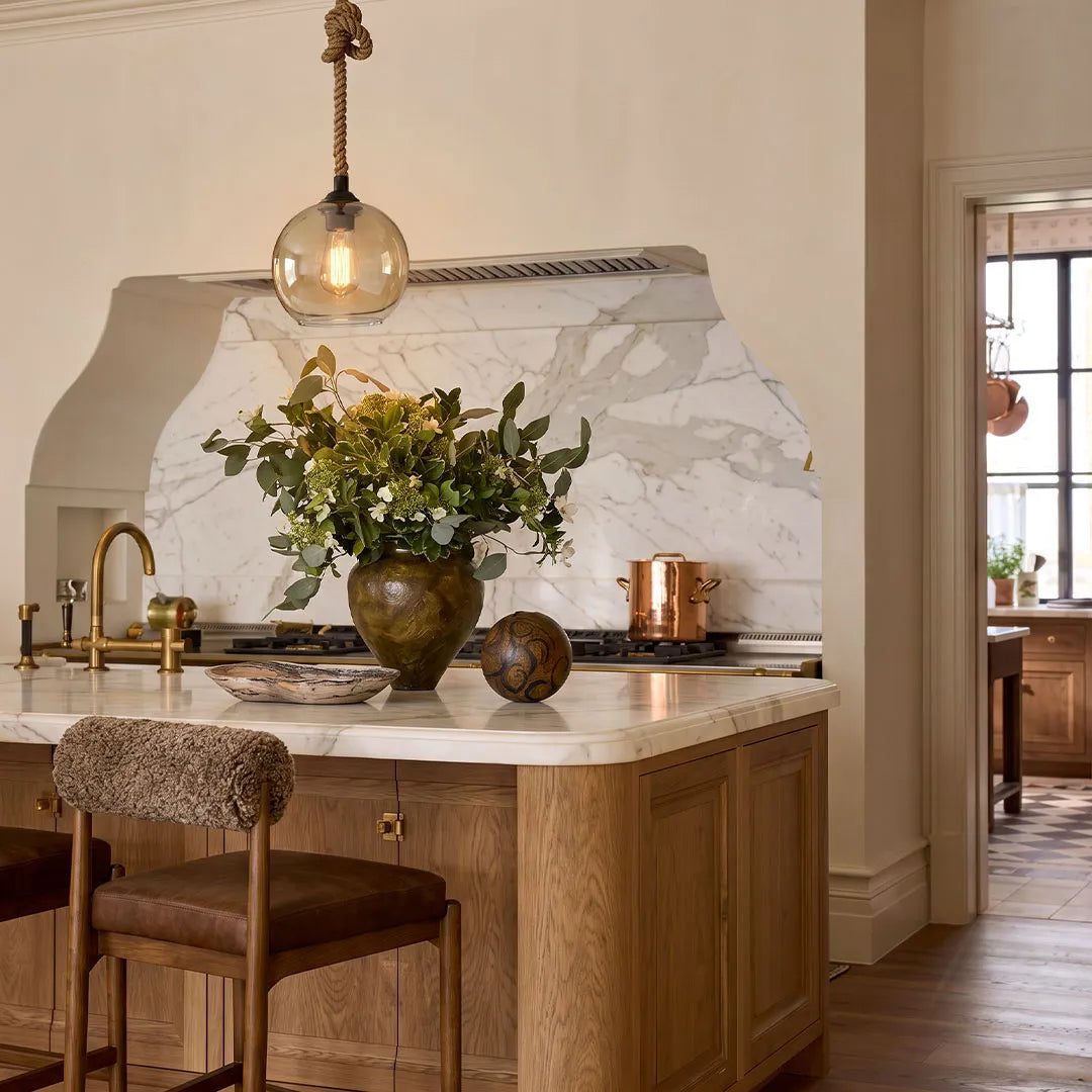 Retro glass pendant light hanging above a marble kitchen island in a warm transitional kitchen.
