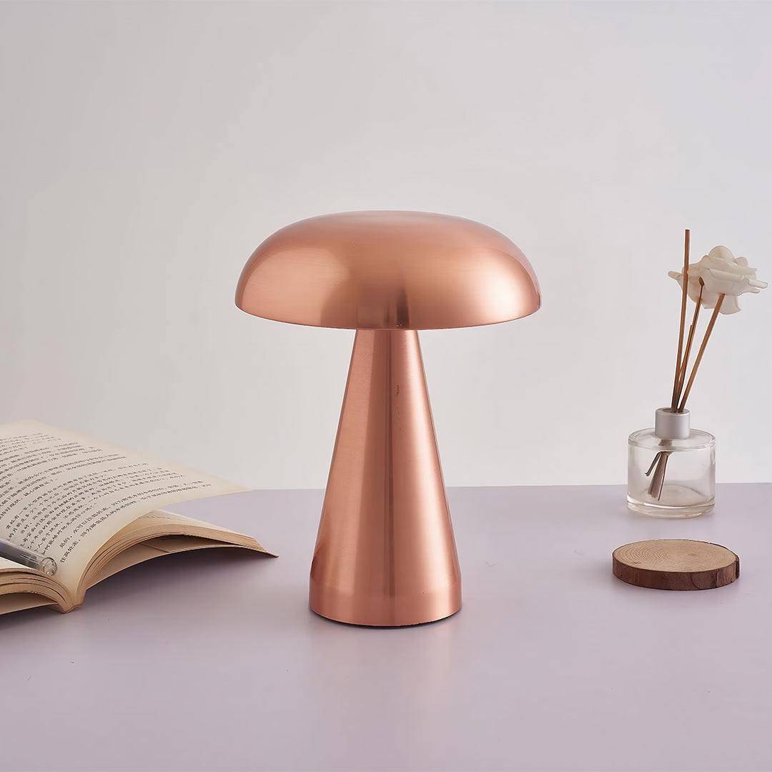 Retro metal table lamp with rose gold shade providing warm glow beside decorative items