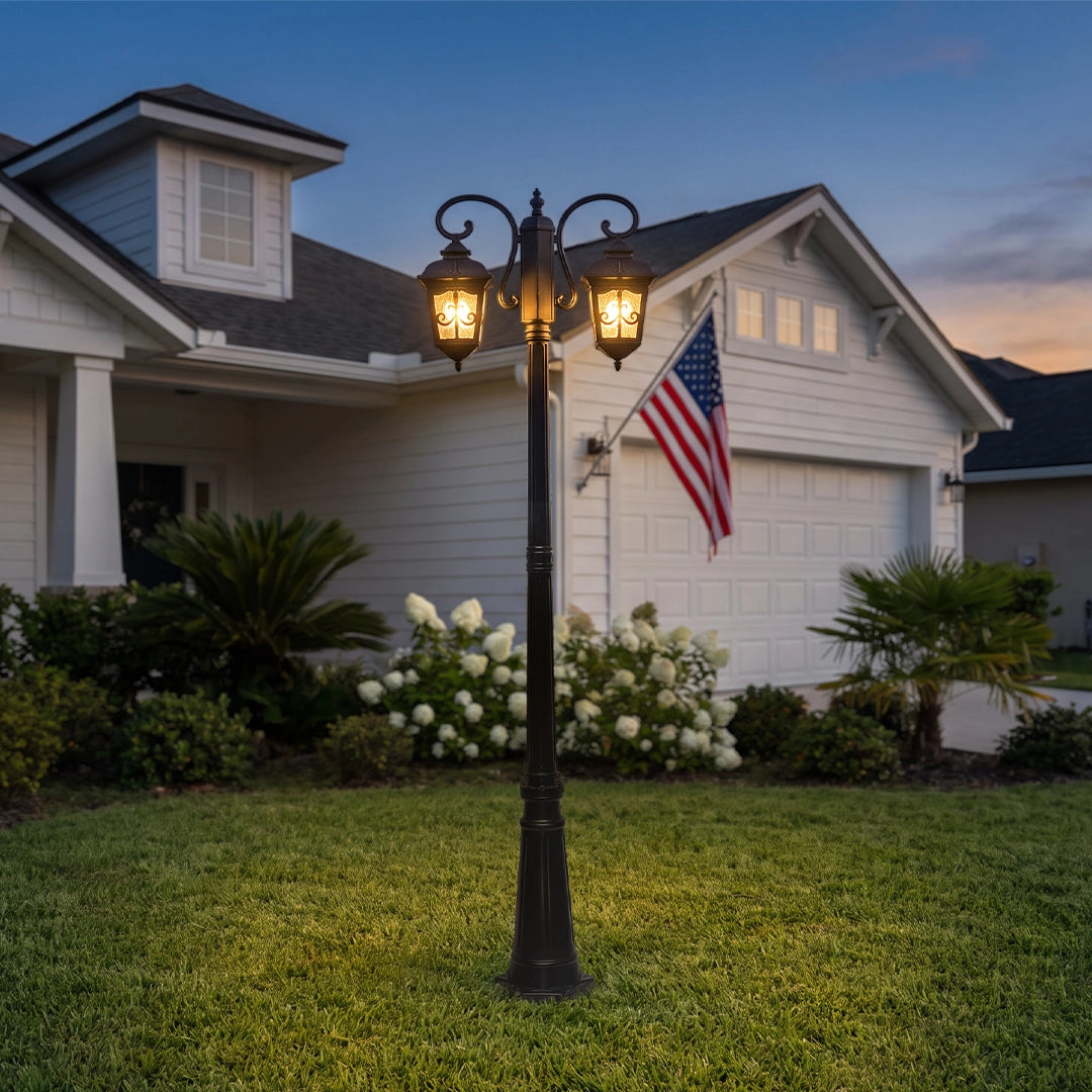 Retro outdoor lamp post standing on a front lawn, featuring twin lantern heads and warm lighting beside a suburban home at dusk.