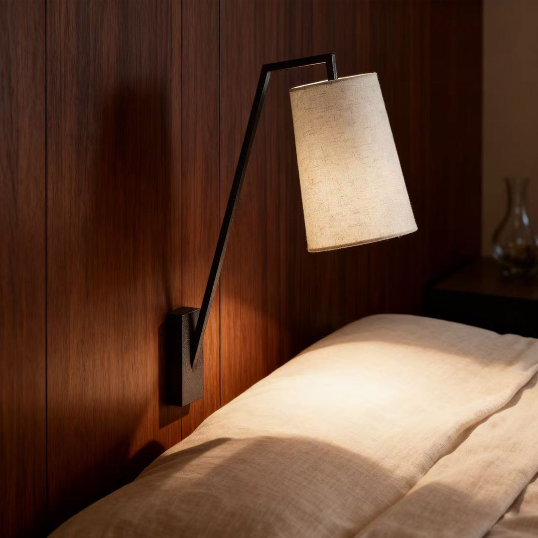 Retro wall lights providing bedside reading light beside bed with warm glow from angled fabric shade