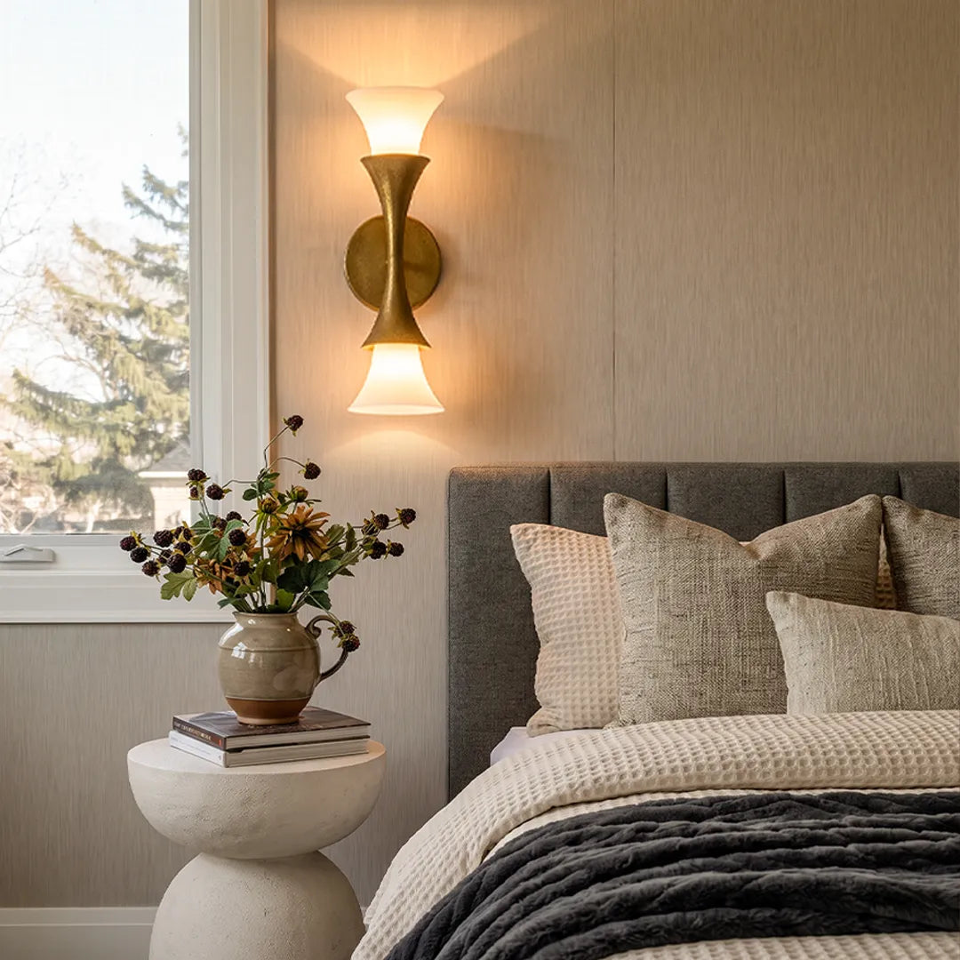 Retro wall sconce mounted beside a bed with a soft frosted shade and warm brass finish.