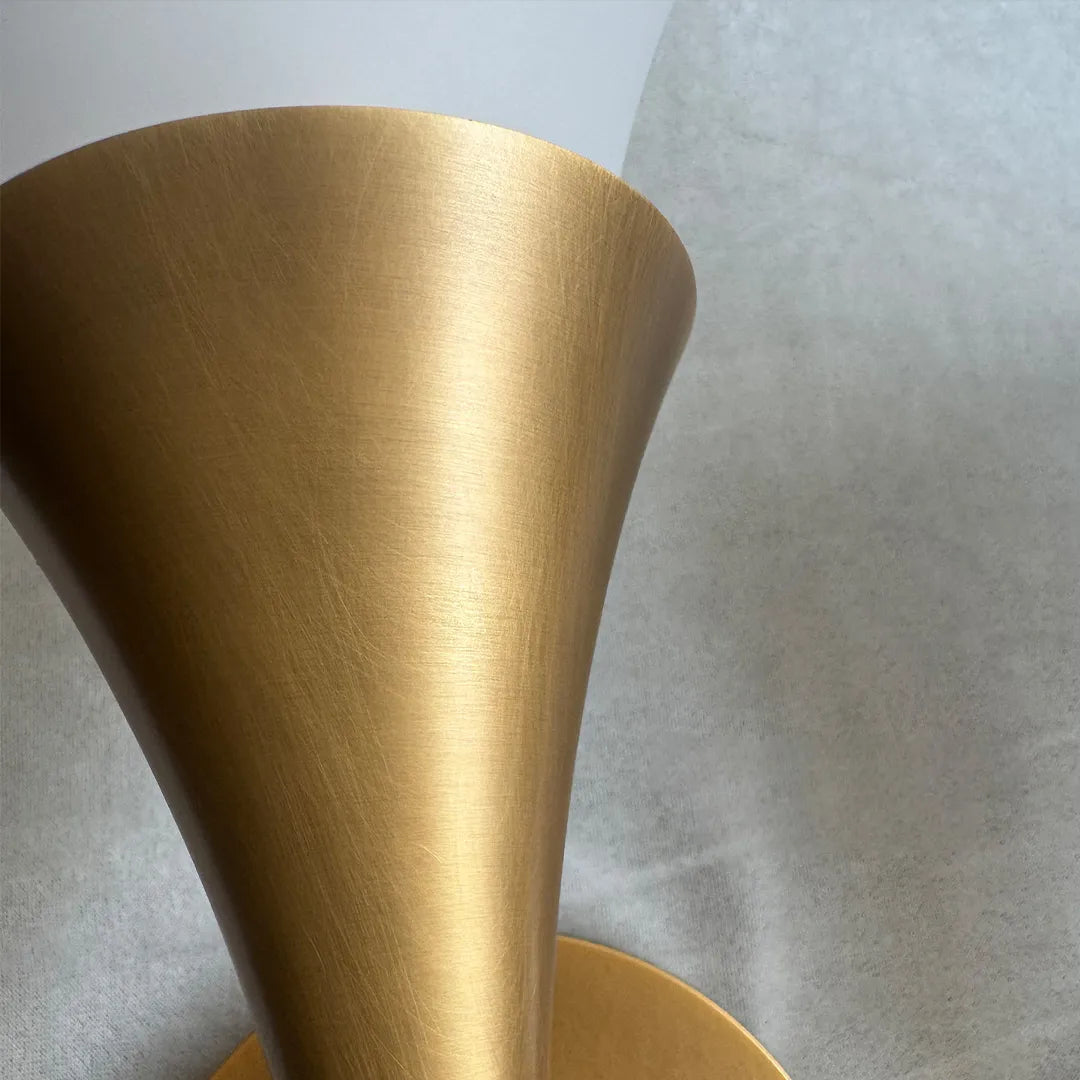 Retro wall sconce close-up showing the brushed brass trumpet-shaped metal detail.