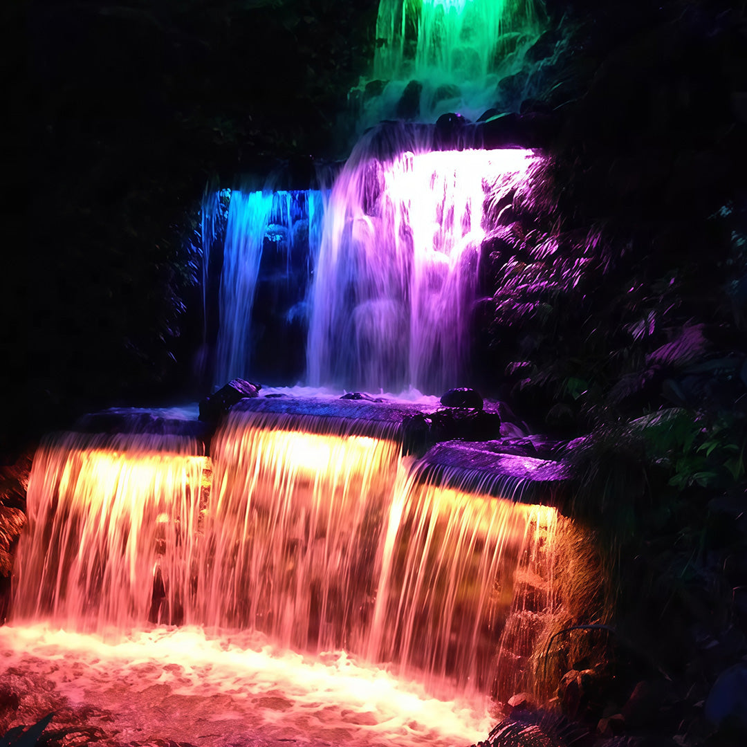 RGB linear wall washer lights creating colorful effects on a garden waterfall.