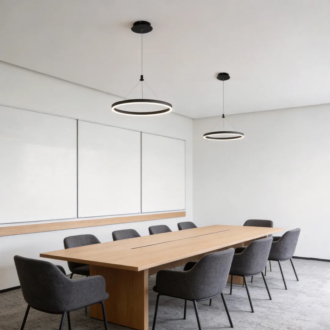 Ring metal chandelier set above a long conference table in a minimalist meeting room with multiple matching fixtures.
