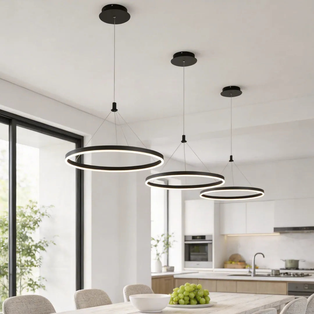 Ring metal chandelier with black circular frame hanging above a modern kitchen island in a bright open interior.