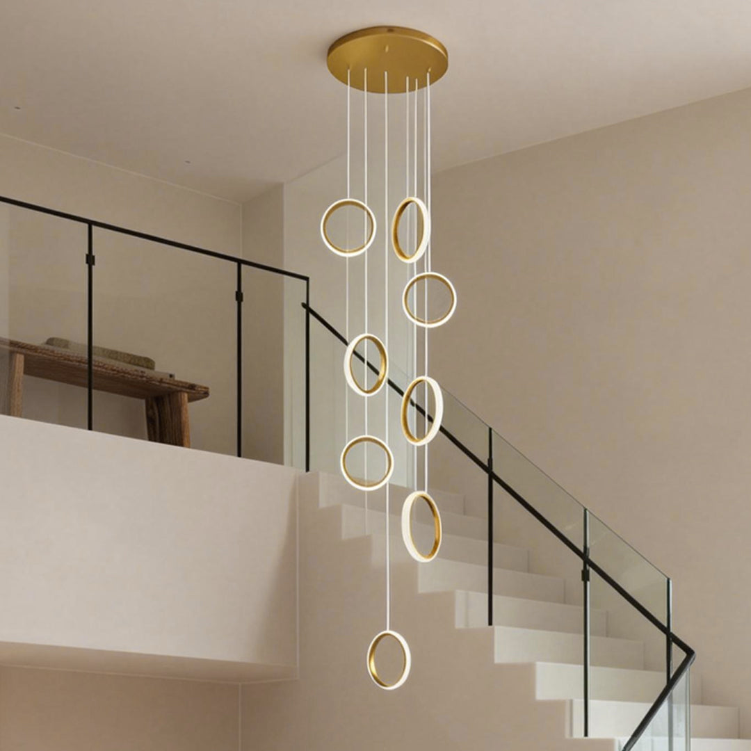 Ring staircase pendant light illuminating a contemporary staircase with glass railings and white walls.